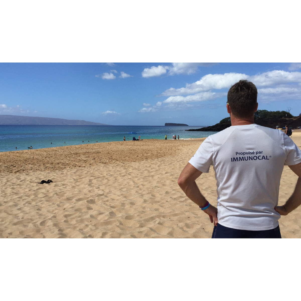Le consultant Immunotec Steve Vermette photographié de dos, affichant fièrement son chandail "Propulsé par Immunocal, admire le paysage paradisiaque de la mer de Maui, Hawaï.
